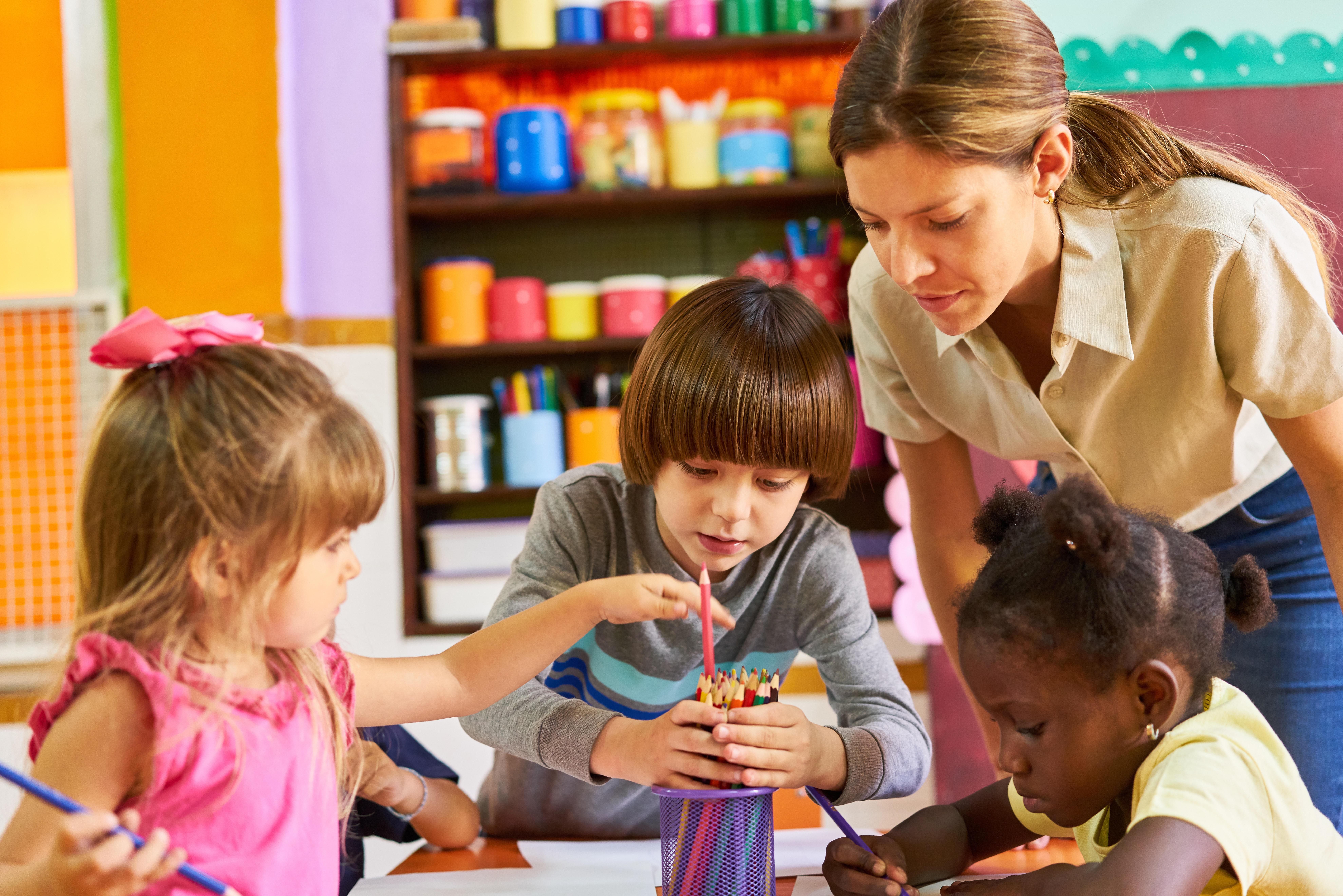 Eine Erzieherin mit malenden Kindern in der Kita. Zugewanderte Erzieher und Pädagoginnen können gegen den Fachkräftemangel in Kitas helfen.