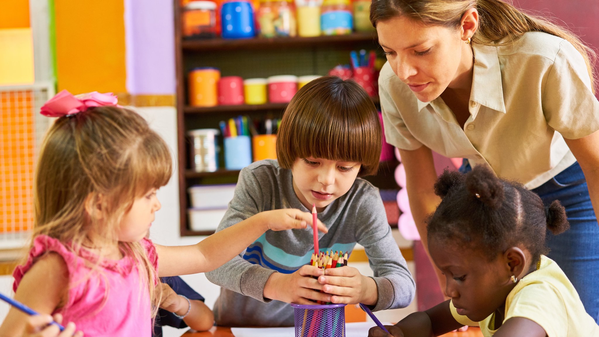 Eine Erzieherin mit malenden Kindern in der Kita. Zugewanderte Erzieher und Pädagoginnen können gegen den Fachkräftemangel in Kitas helfen.