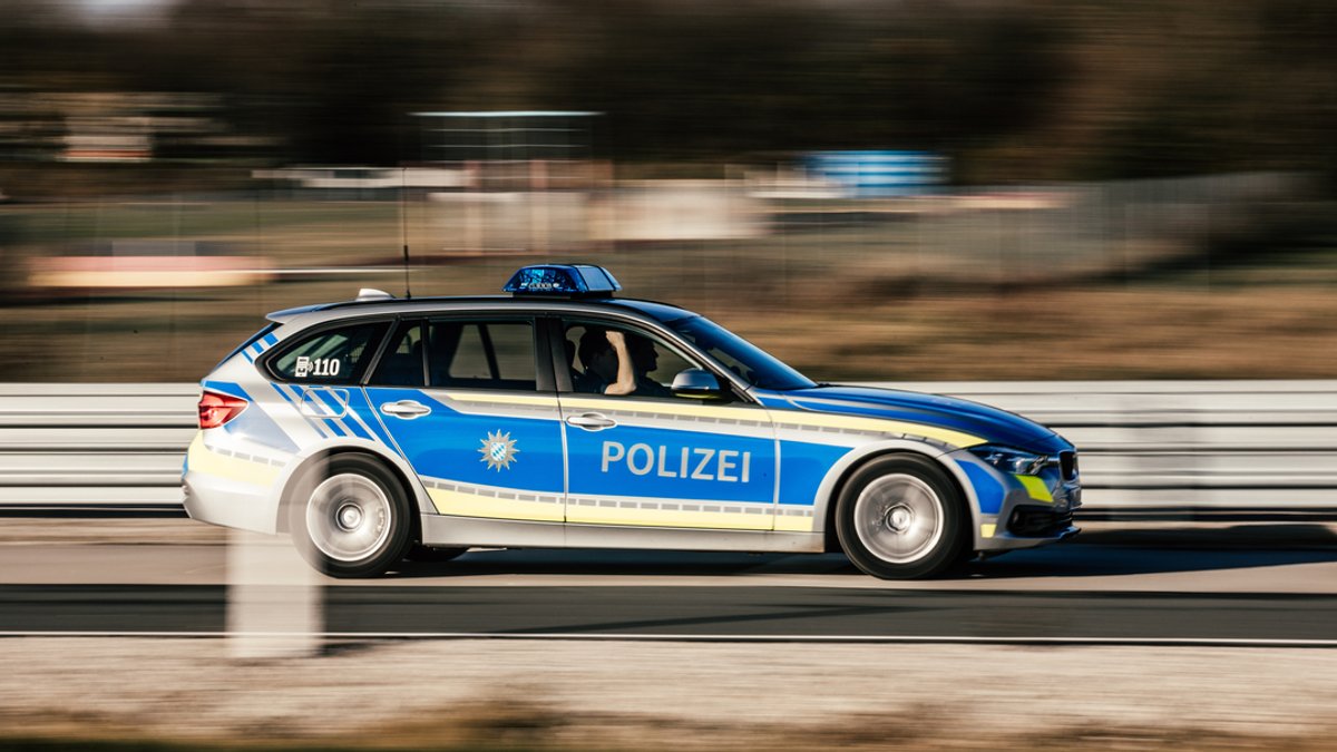 Ein Polizeiauto fährt mit Blaulicht auf einer Landstraße.
