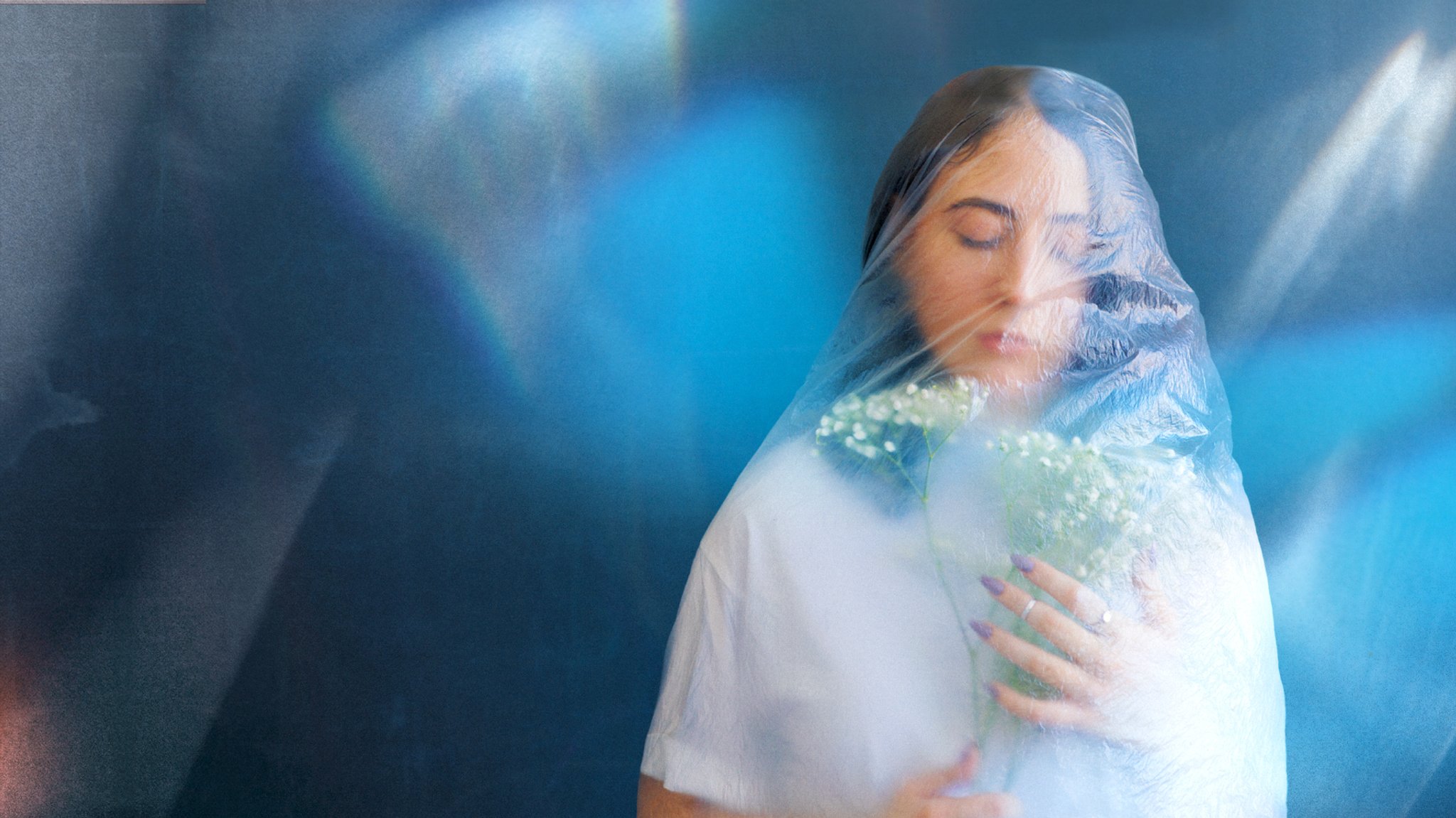 Eine Frau mit Blumen in der Hand, die eine Plastikfolie als Schleier trägt.