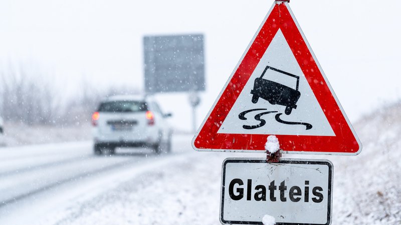 Verschneite Straße mit Verkehrsschild "Glatteis" | Bild: picture alliance / CHROMORANGE | Michael Bihlmayer Verschneite Straße mit Verkehrsschild "Glatteis"