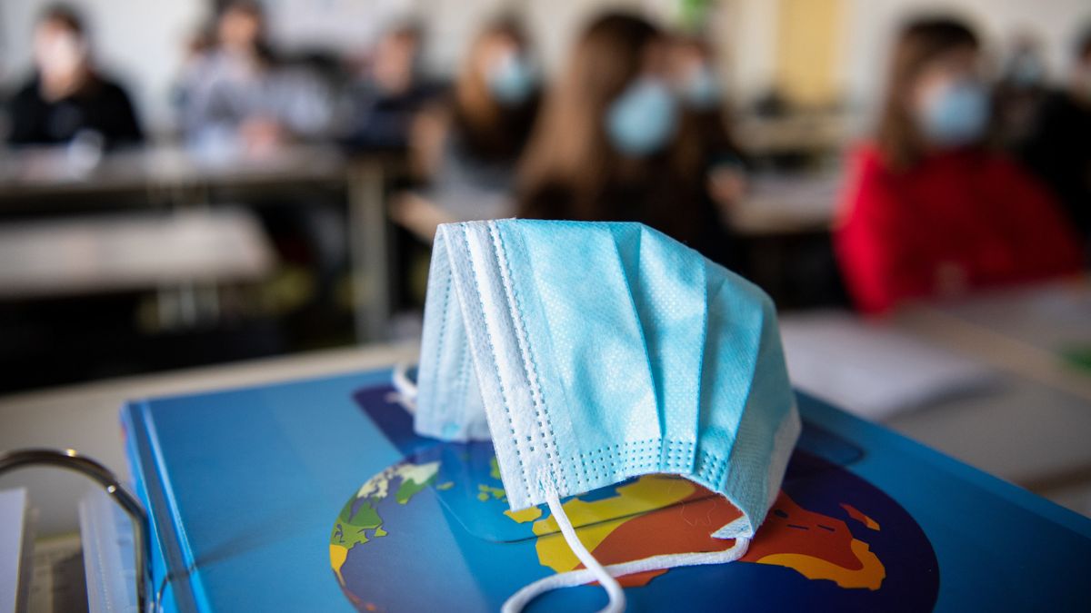 Eine Maske auf einem Weltatlas in einem Klassenzimmer mit Präsenzunterricht