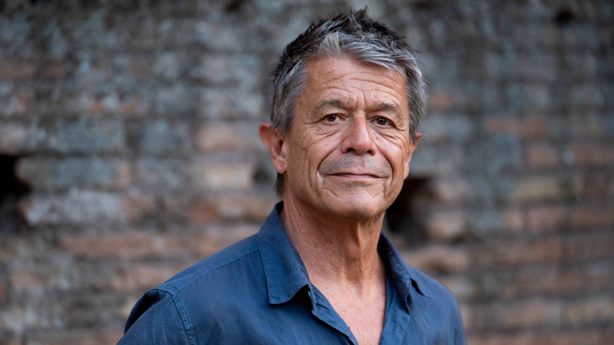 Der französische Schriftsteller, Drehbuchautor und Regisseur Emmanuel Carrère steht vor einer Backsteinwand. | Bild: picture alliance / NurPhoto | Massimo Valicchia Der französische Schriftsteller, Drehbuchautor und Regisseur Emmanuel Carrère steht vor einer Backsteinwand.