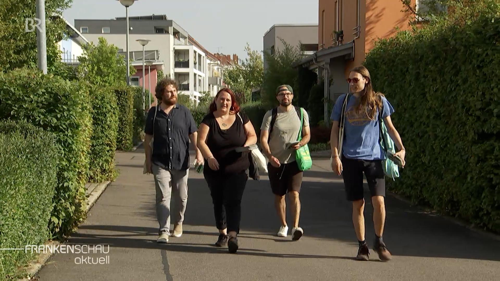 Eine Frau und drei Männer gehen eine Straße entlang. 