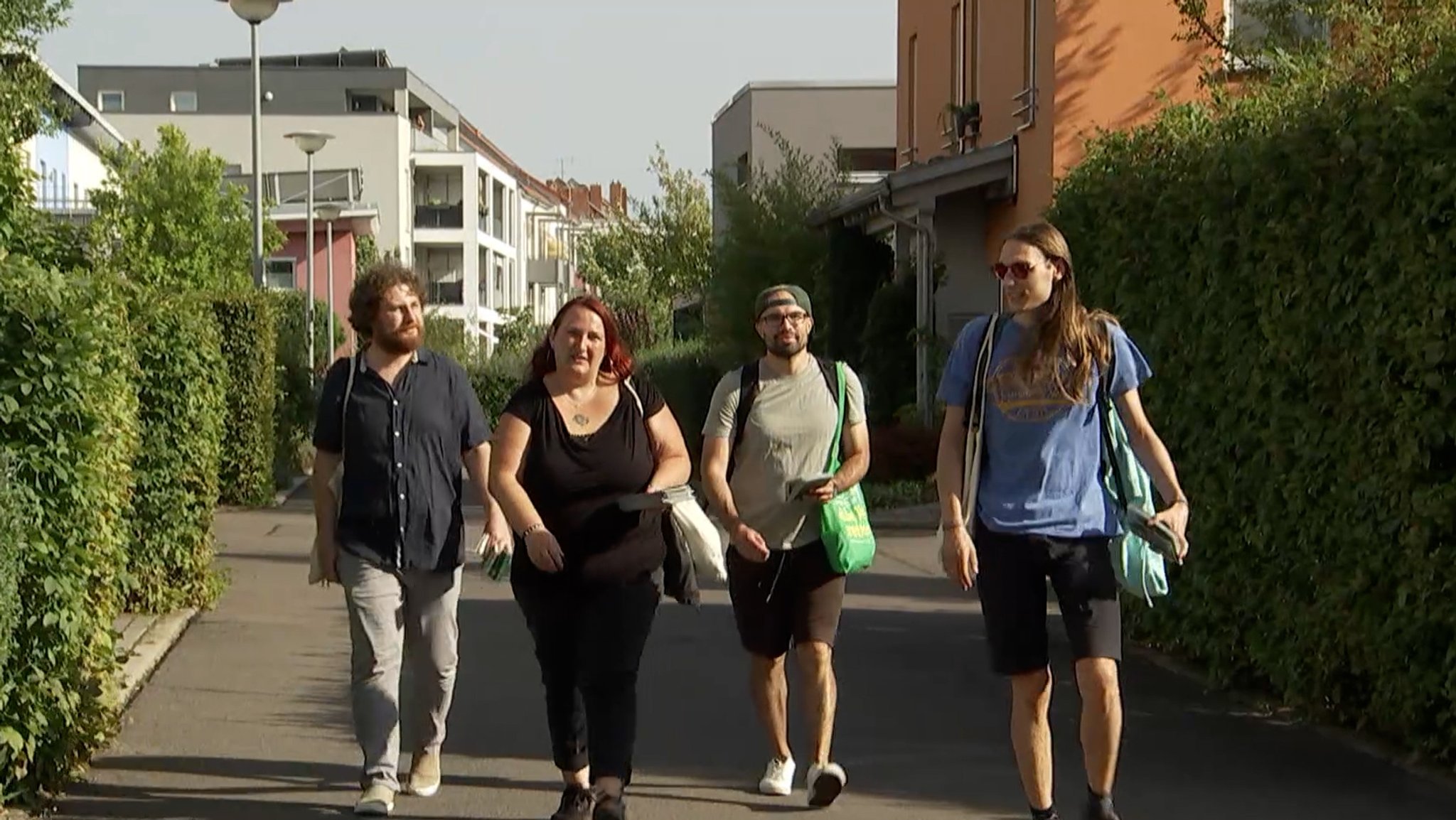 Eine Frau und drei Männer gehen eine Straße entlang. 