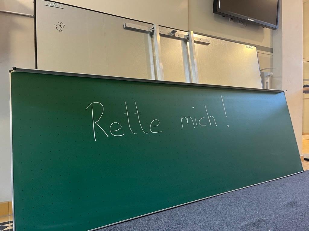 "Rette mich!", steht auf einer Schultafel. 