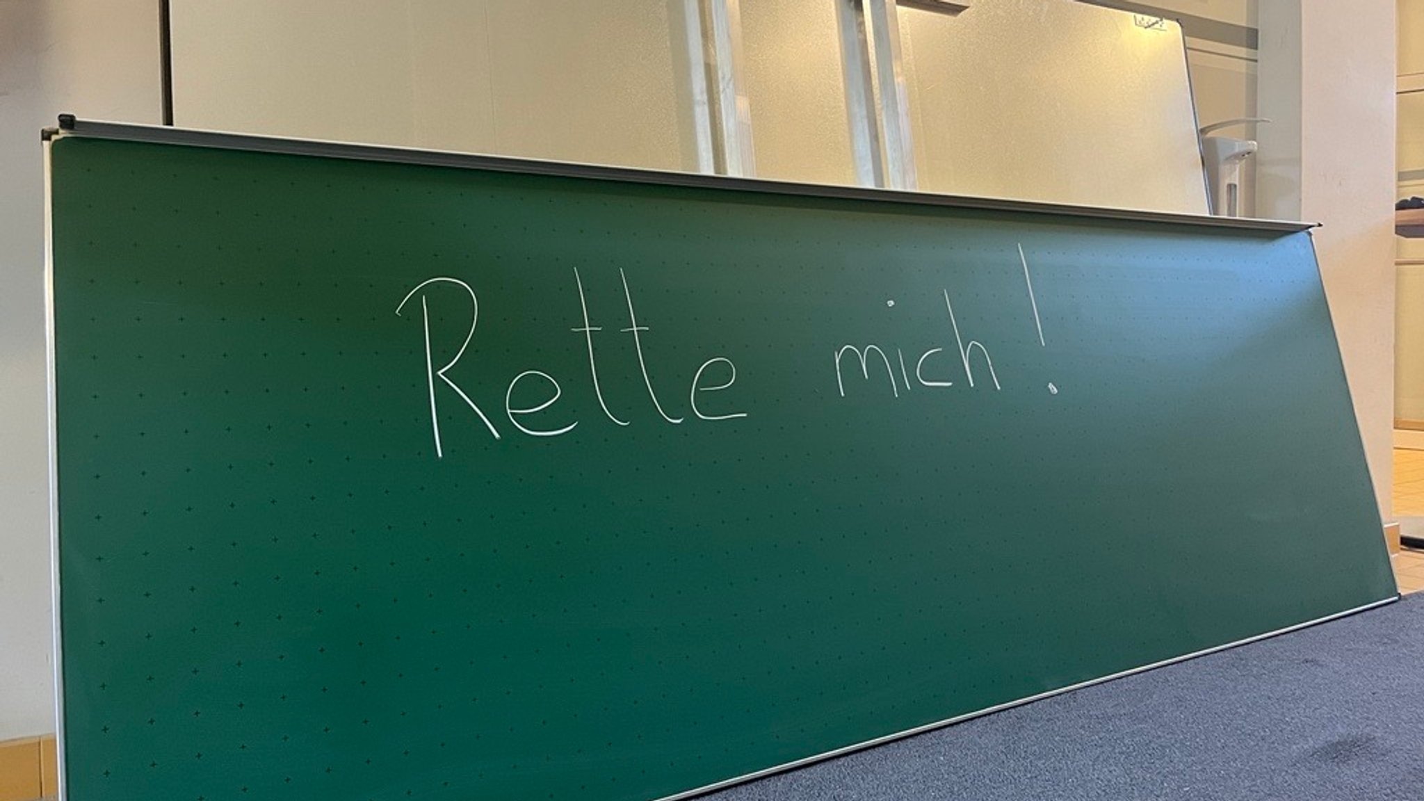 "Rette mich!", steht auf einer Schultafel. 