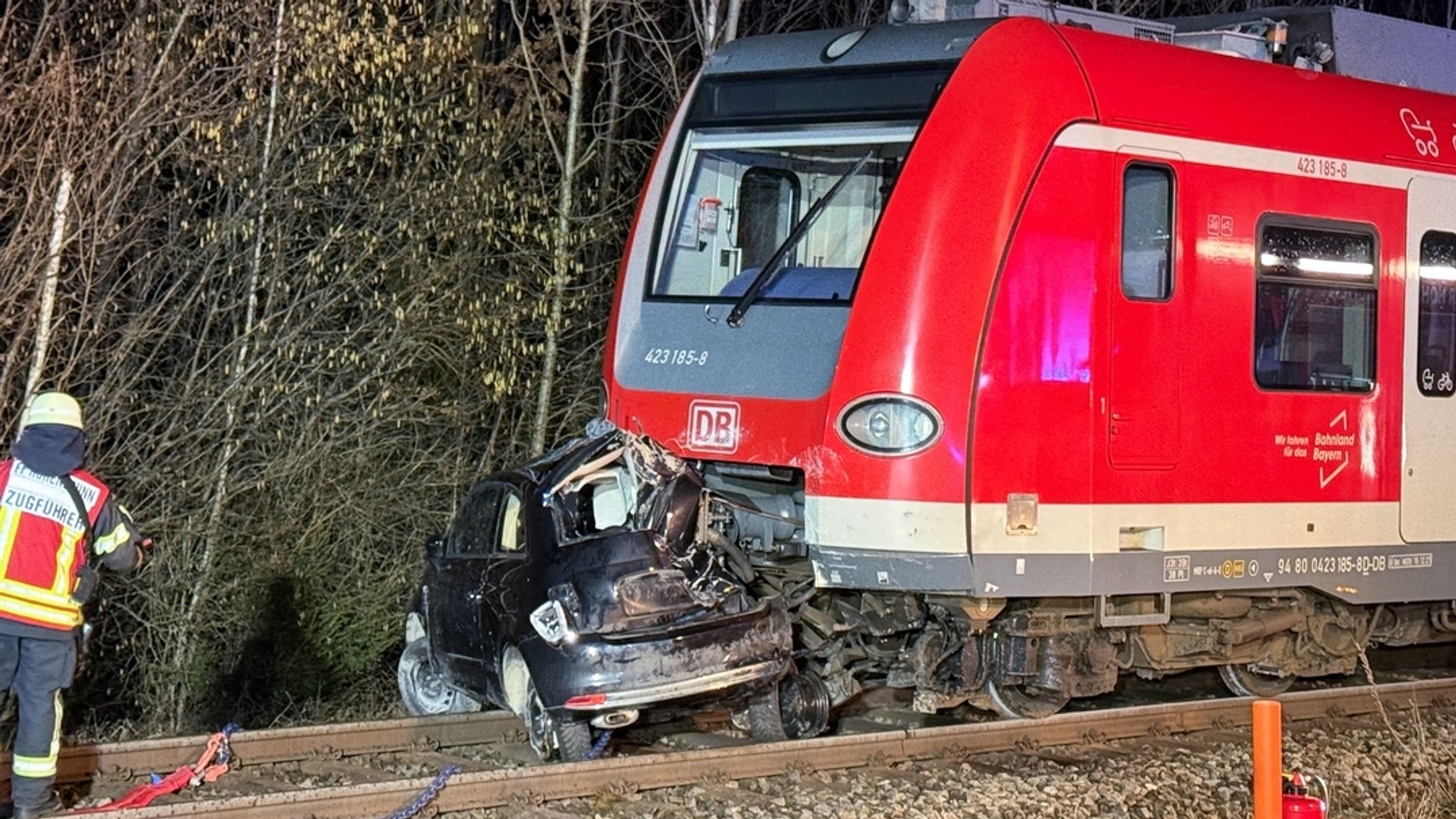 12.02.2026, Bayern, Höhenkirchen-Siegertsbrunn: Ein zerstörter PKW steht nach einem Unfall vor einem S-Bahn-Zug in Höhenkirchen-Siegertsbrunn.