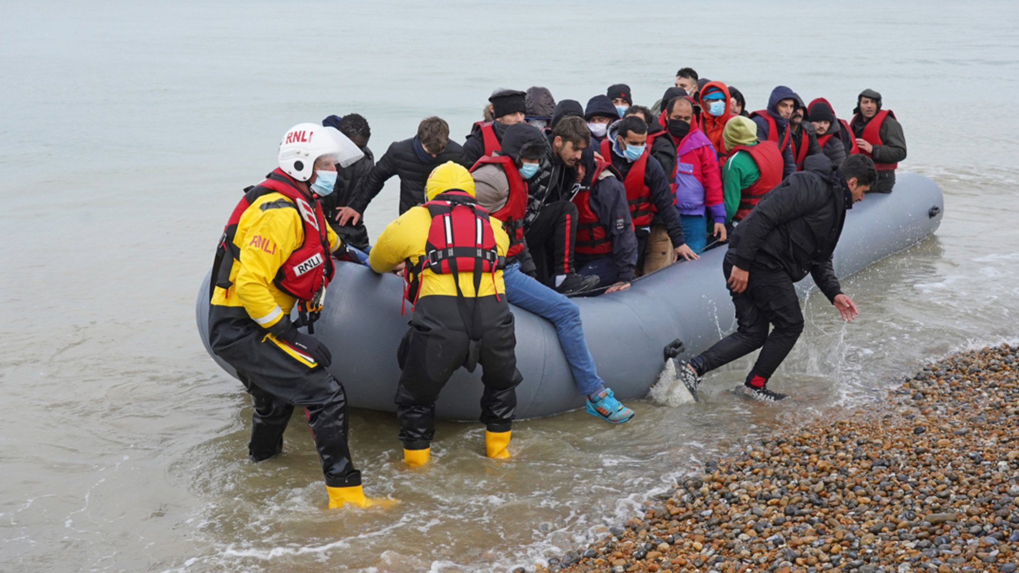 Mitglieder einer Rettungsbootbesatzung helfen am 20.11.21 Menschen, bei denen es sich vermutlich um Migranten handelt, aus einem Schlauchboot.