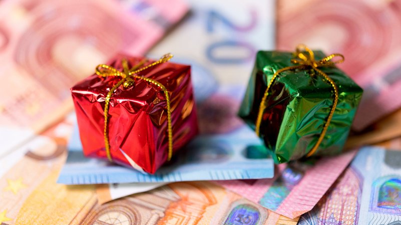 Zwei kleine Weihnachtsgeschenke sind auf Geldscheinen plaziert. | Bild: dpa-Bildfunk/Monika Skolimowska Zwei kleine Weihnachtsgeschenke sind auf Geldscheinen plaziert.