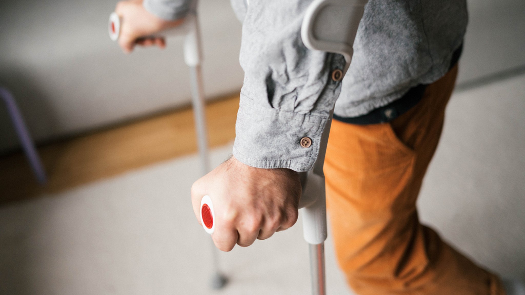 Ein Mann, der sich auf Krücken durch einen Raum bewegt.