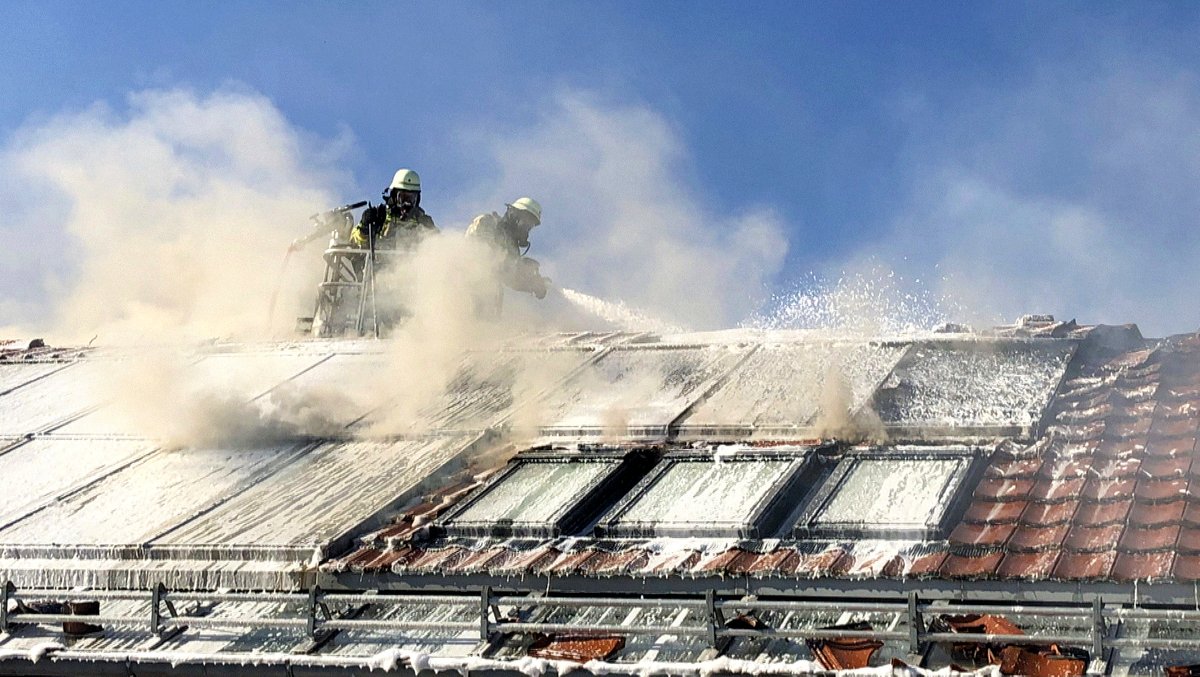 Feuerwehrmänner löschen in Brand geratene Solarthermie-Panel.