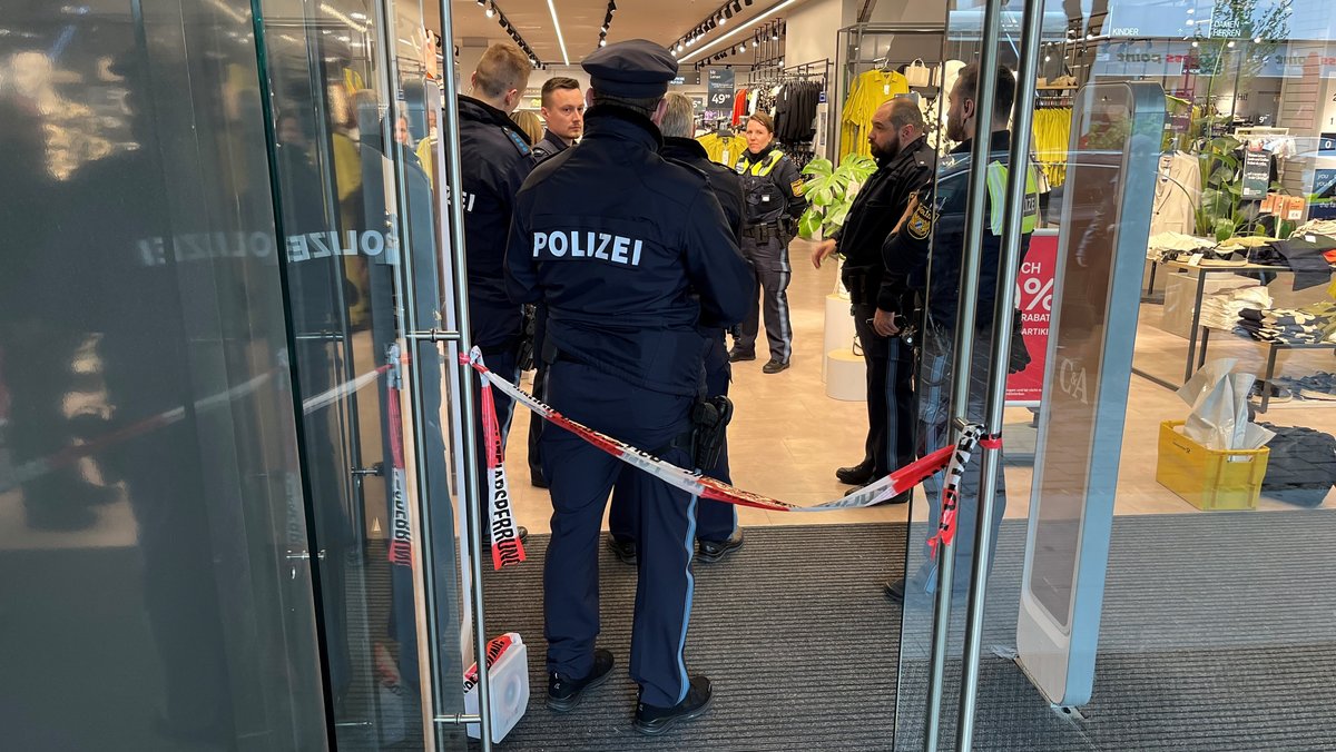 Polizeibeamte am Eingang zu einem Augsburger Bekleidungsgeschäft, nachdem in mehreren Läden Feuer gelegt worden war. 