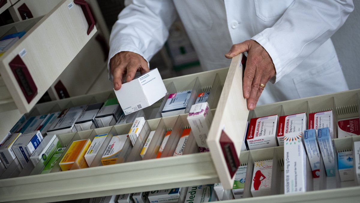 Ein Apotheker holt eine Medikamentenverpackung aus einer Schublade in einer Apotheke (Symbolbild)