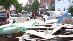 In Günzburg stehen Anwohner in Gummistiefeln auf der Straße, für die Sperrmüll-Abholung aufgetürmt liegen um sie herum Dinge, die vom Hochwasser zerstört wurden. | Bild:BR/Wiesbeck, Til Antonie