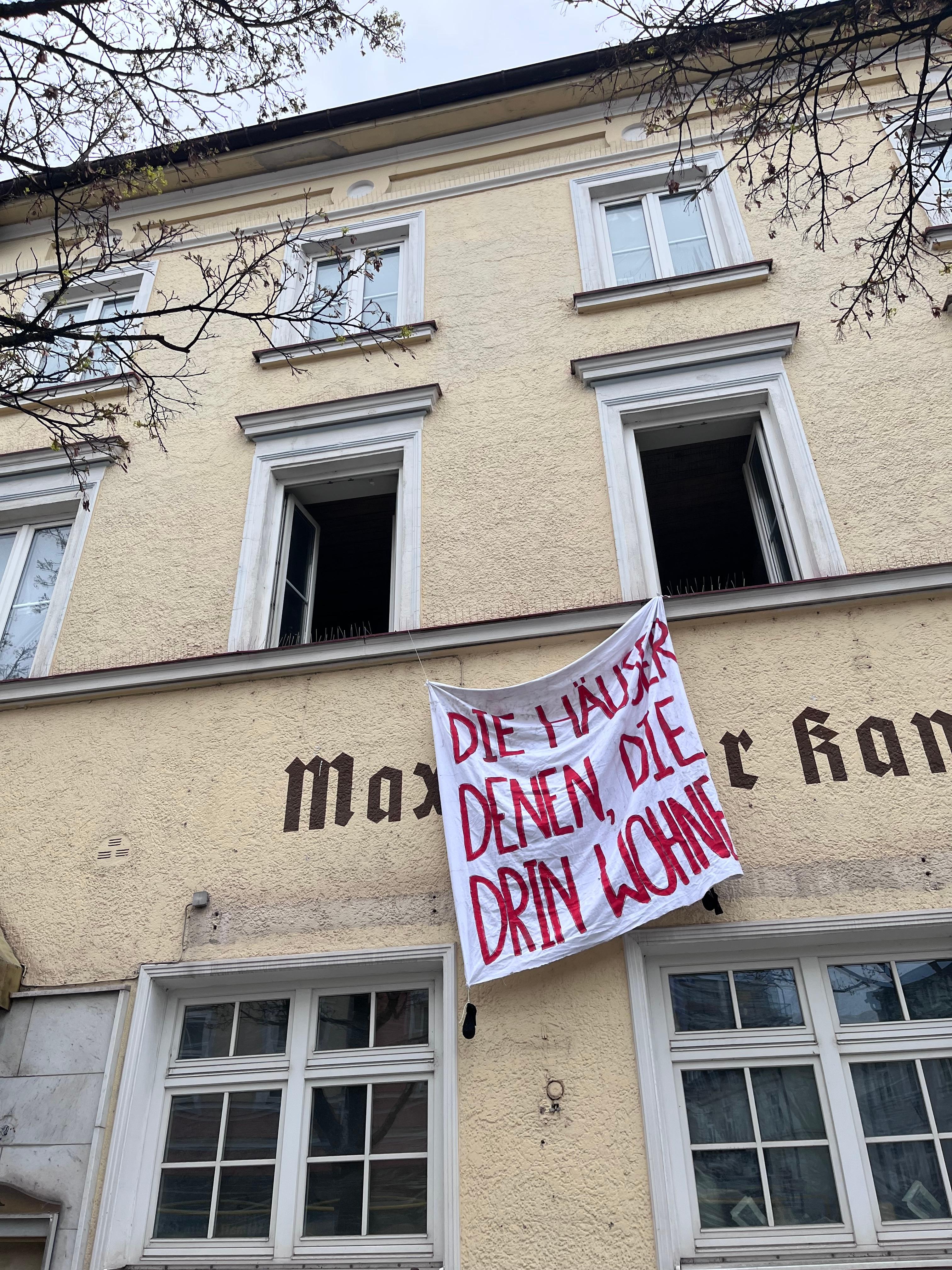 Zu sehen ist ein Transparent, auf dem "Die Häuser denen, die drin wohnen" steht. 