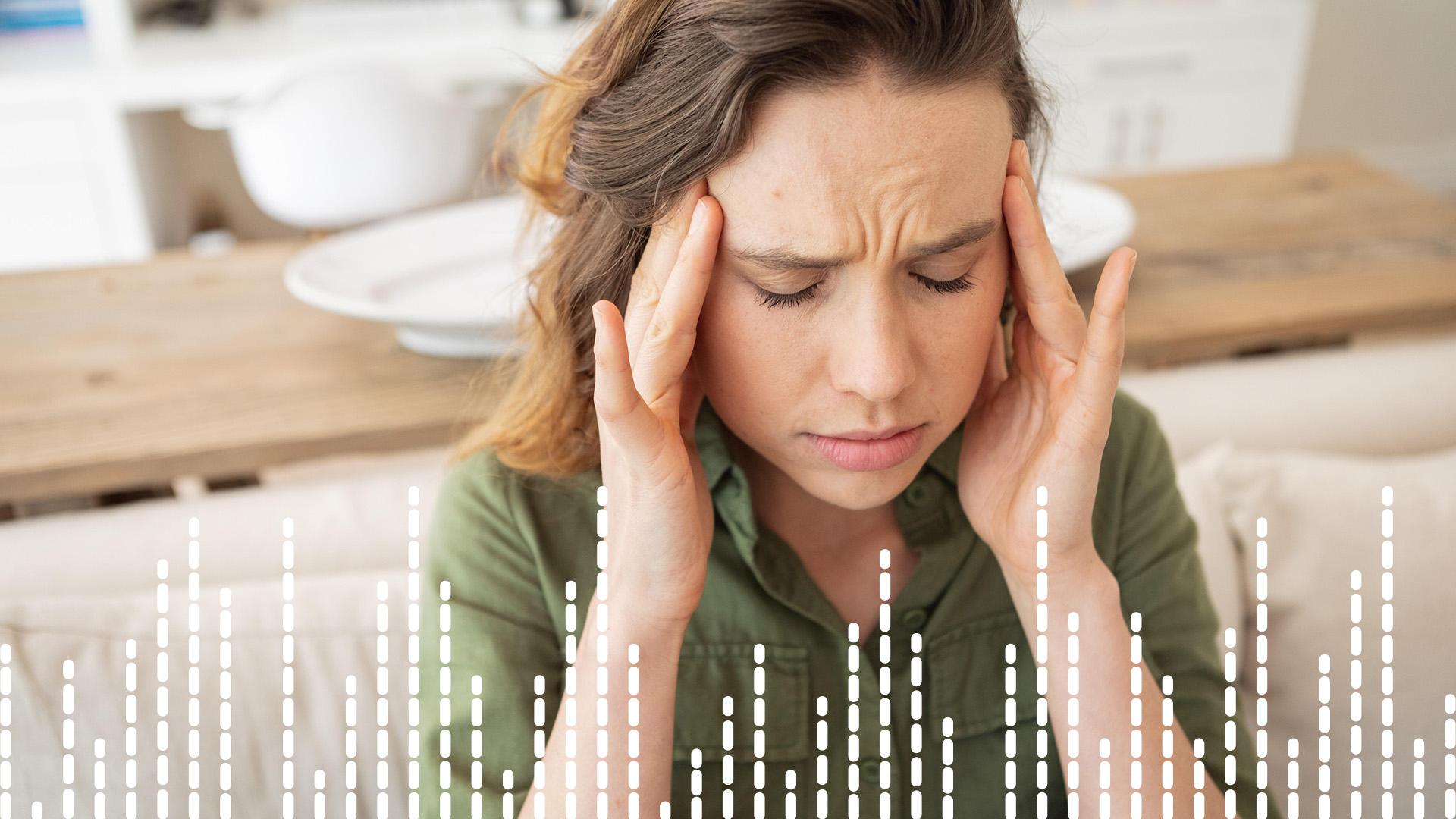 Junge Frau fasst sich an die Schläfen. 