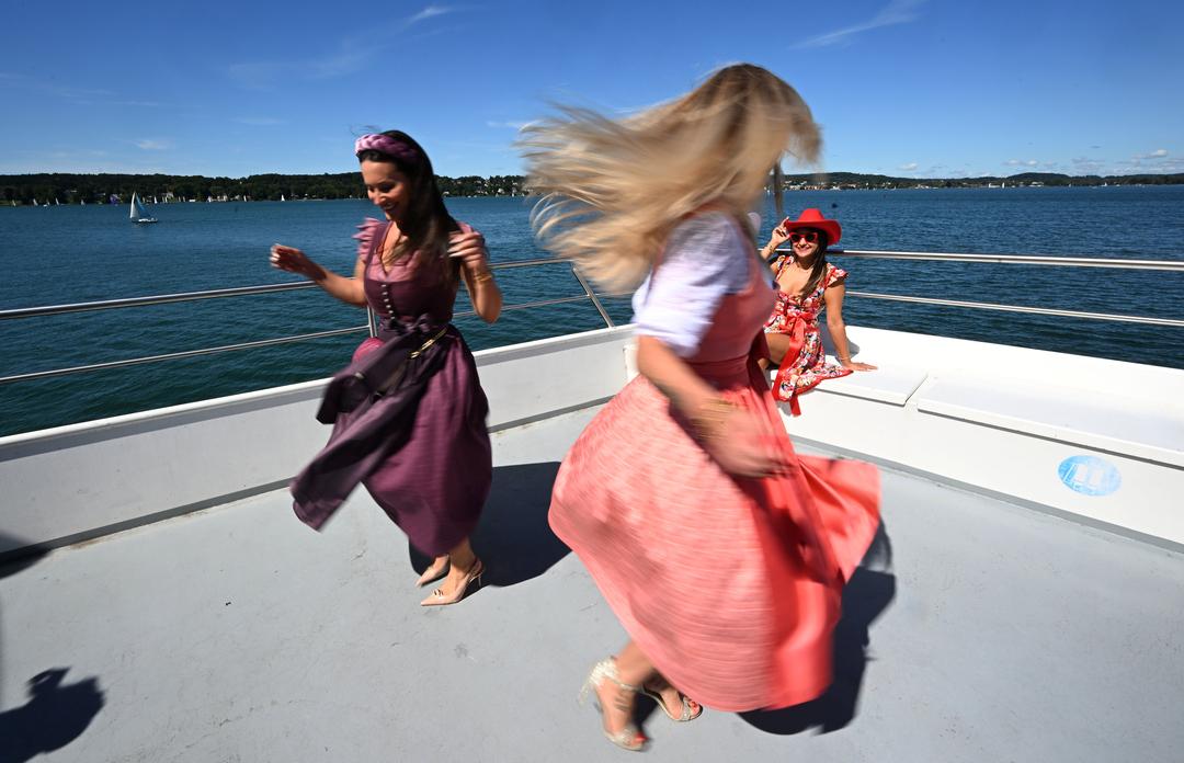Die Models Rebecca Fiedler (l) und Nicole Böttinger tanzen bei einer Trachtenmoden-Fahrt mit dem Schiff "Seeshaupt" der Bayerischen Seenschifffahrt über den Starnberger See. 