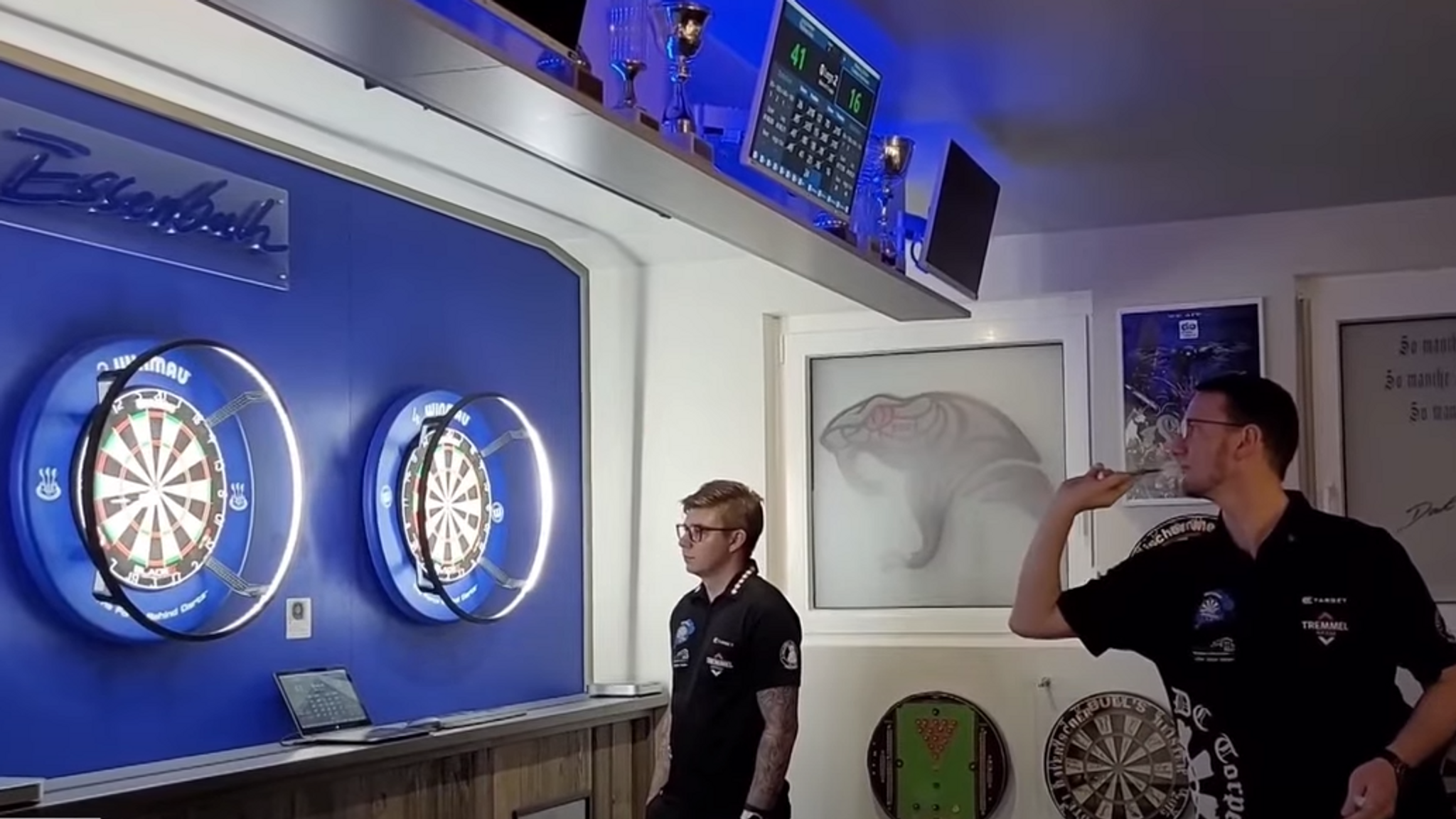 Ein Dartsportler wirft einen Pfeil auf eine Dartscheibe. 