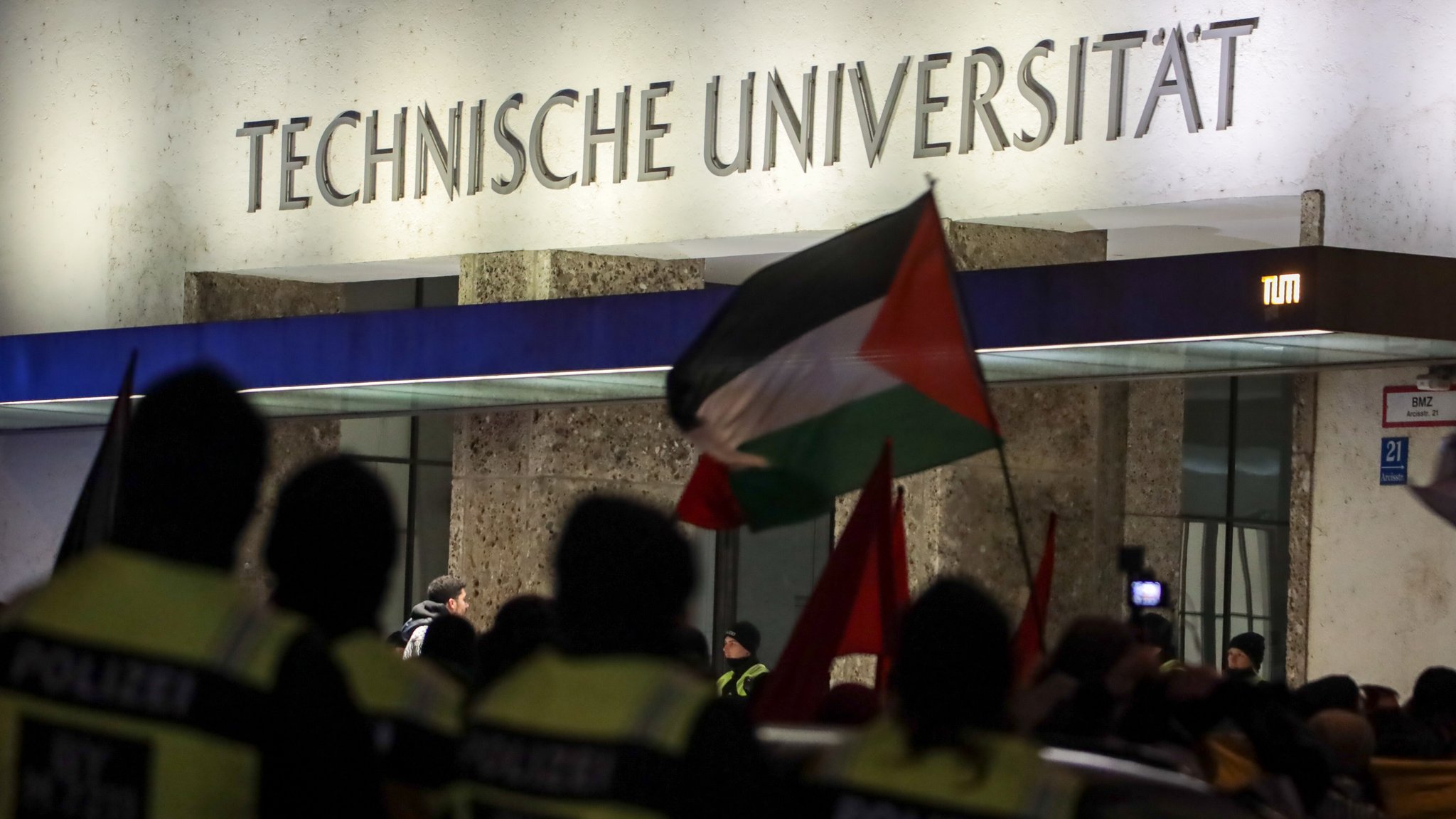 Zu sehen sind das Gebäude der TU München und Demonstranten mit Fahnen | Bild: picture alliance / ZUMAPRESS.com | Julius Mortsi Zu sehen sind das Gebäude der TU München und Demonstranten mit Fahnen