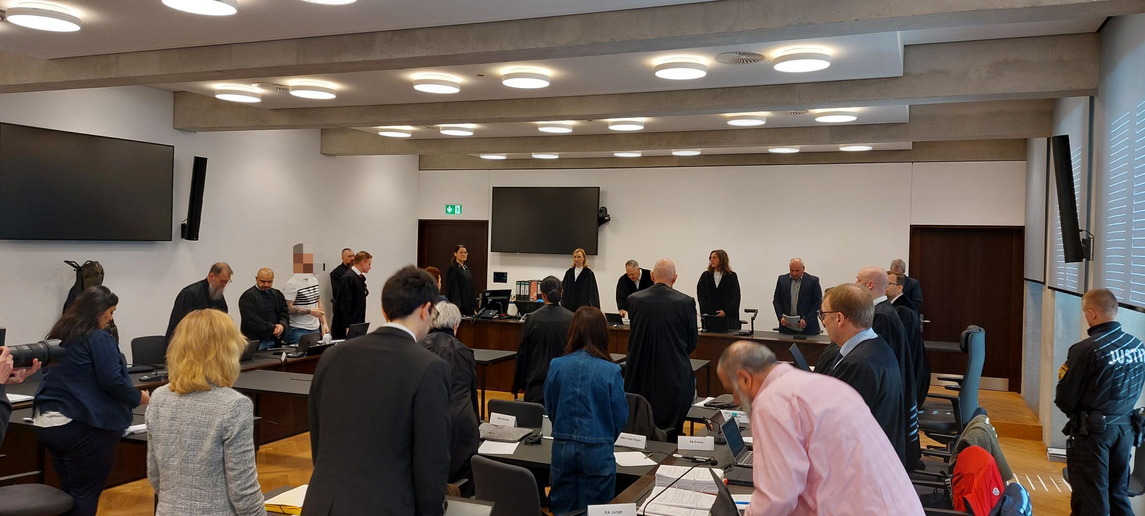 Angeklagter gepixelt mit seinen Verteidigern und weiteren Prozessbeteiligten im Gerichtssaal.