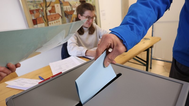 22.03.2026, Bayern, Landsberg am Lech: Ein Wähler wirft bei der Stichwahl zur Landratswahl im Rathaus seinen Stimmzettel in eine Wahlurne. | Bild: dpa-Bildfunk/Karl-Josef Hildenbrand 22.03.2026, Bayern, Landsberg am Lech: Ein Wähler wirft bei der Stichwahl zur Landratswahl im Rathaus seinen Stimmzettel in eine Wahlurne.