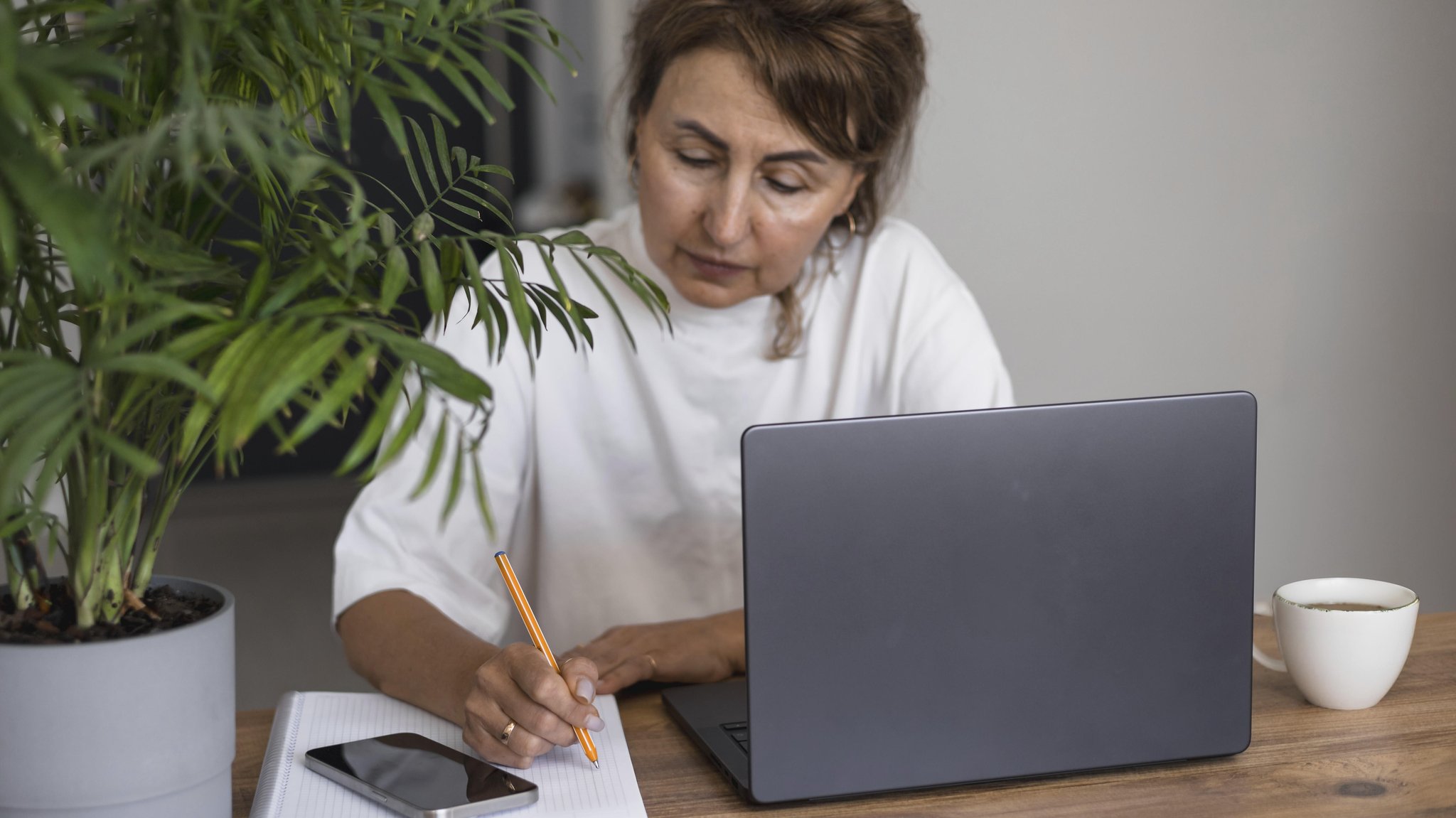 Eine Frau notiert sich etwas, während sie am Laptop sitzt. (Symbolbild) | Bild: dpa/pa/imageBROKER/Alina Kandybka Eine Frau notiert sich etwas, während sie am Laptop sitzt. (Symbolbild)