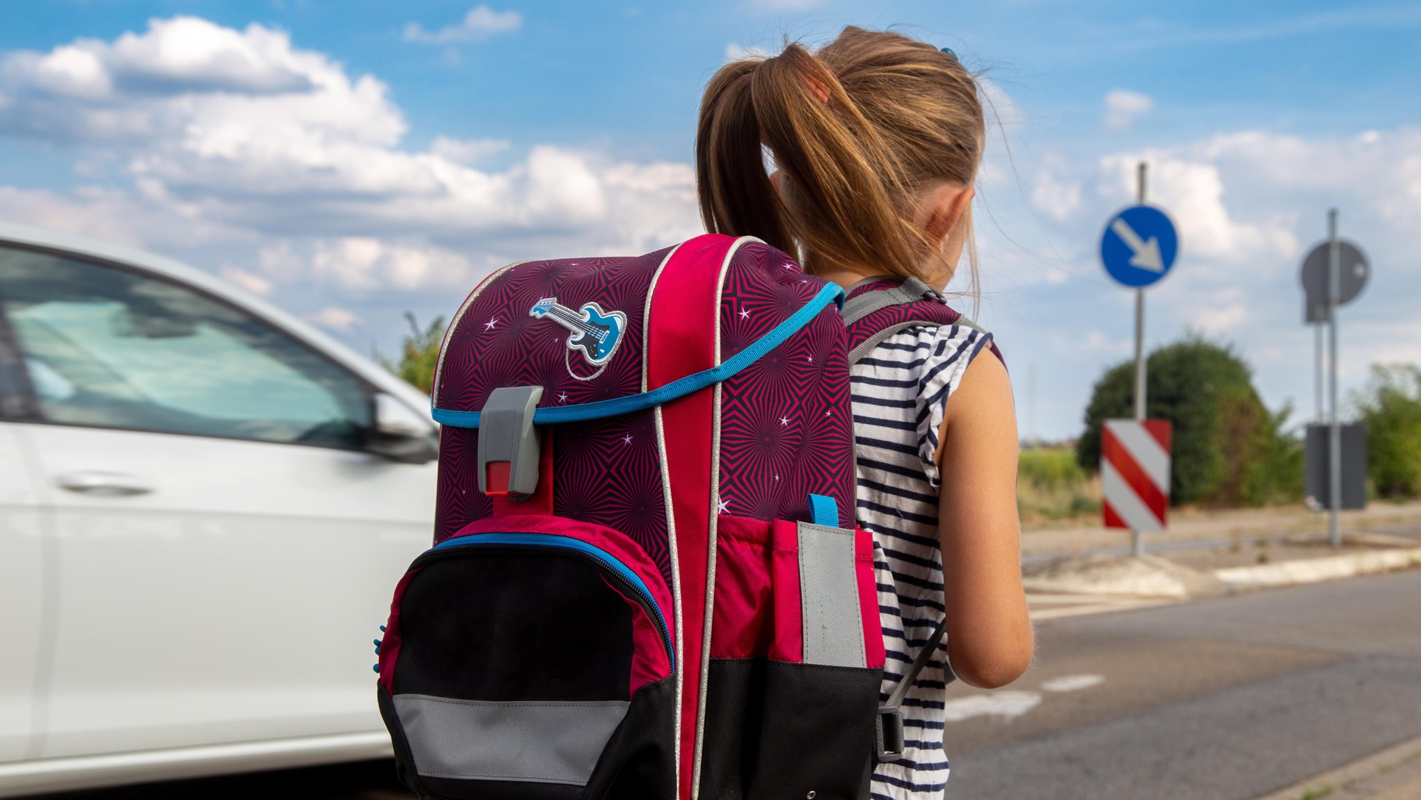 Symbolbild: Ein Kind läuft auf dem Schulweg, ein Auto überholt das Kind auf der linken Seite. | Bild: picture alliance / CHROMORANGE | Udo Herrmann Symbolbild: Ein Kind läuft auf dem Schulweg, ein Auto überholt das Kind auf der linken Seite.
