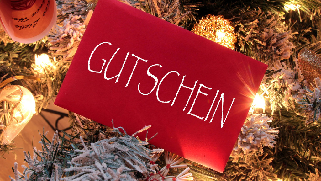 Gutschein im roten Briefumschlag vor weihnachtlicher Dekoration