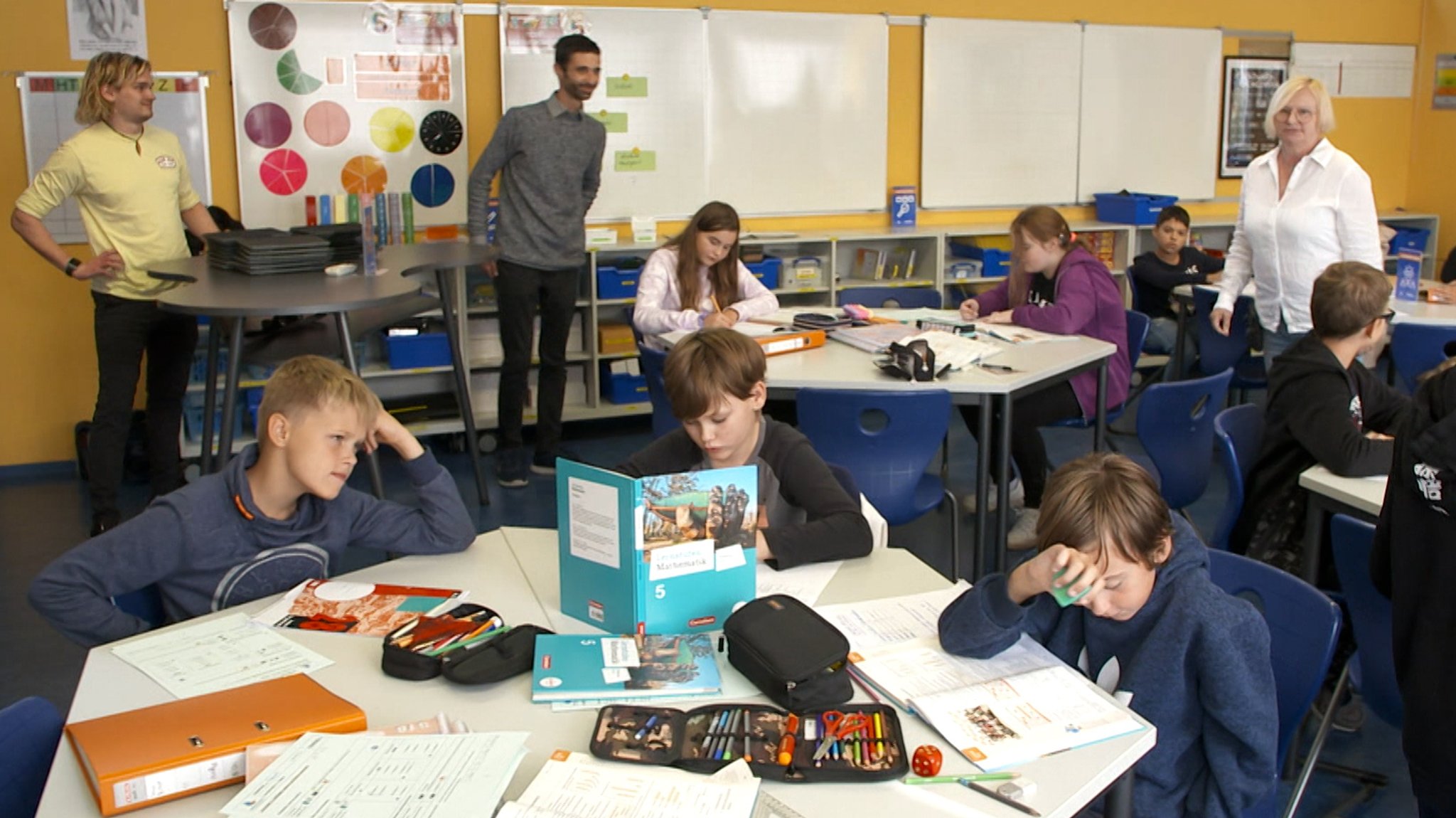 Ein Klassenzimmer mit Arbeitsinseln, an denen Kinder sitzen und lernen.