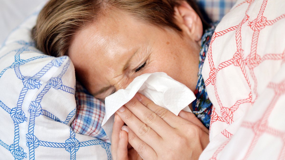 Eine Frau liegt mit einem Erkältungsinfekt im Bett (Symbolbild)