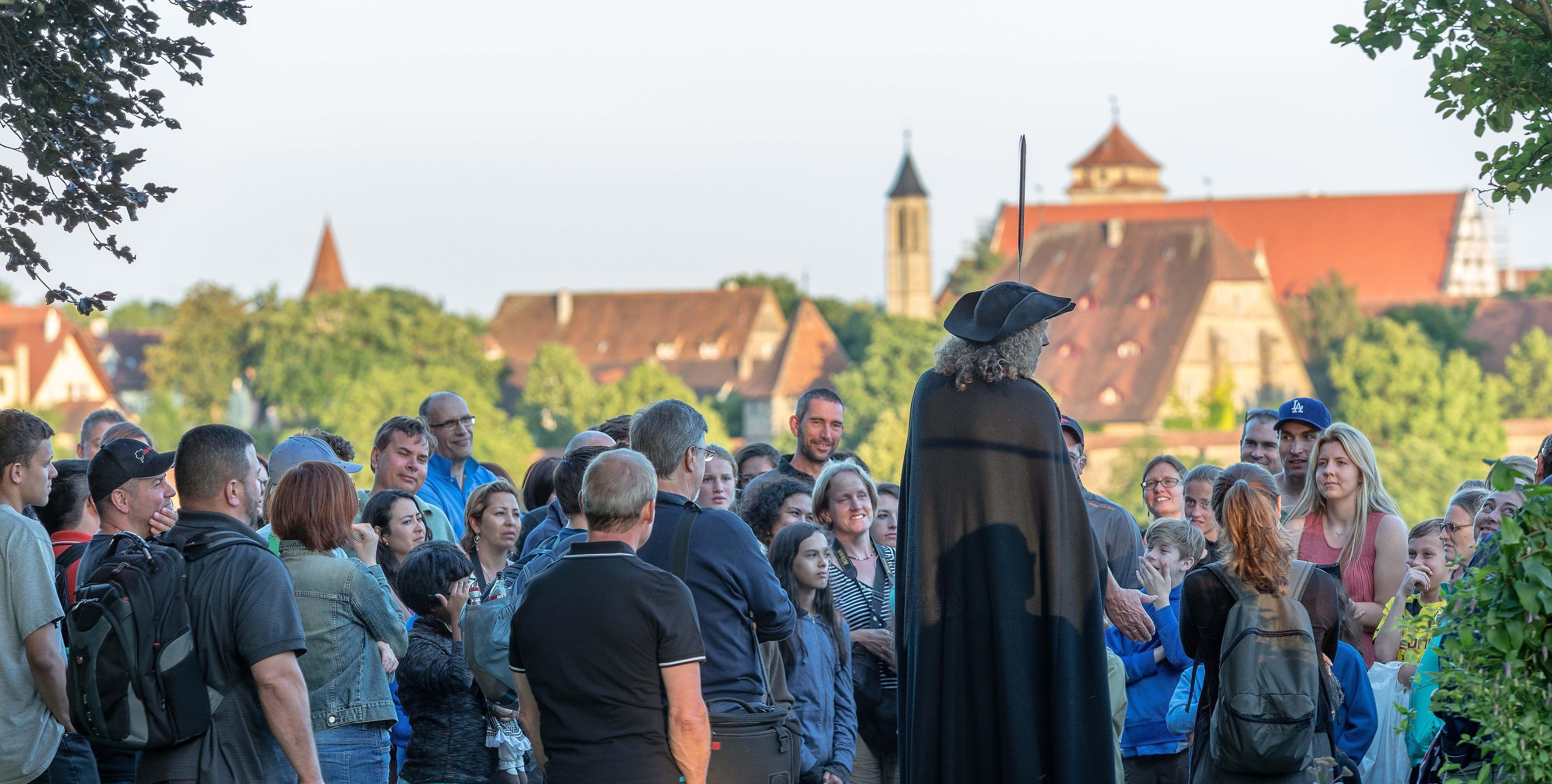 Ein Nachtwächter redet vor Publikum in Rothenburg ob der Tauber. 