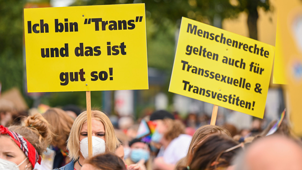 Eine Szene beim Christopher Street Day September 2021 in Oldenburg: Man sieht Plakate mit Aufschriften wie "Ich bin >Trans< und das ist gut so!"