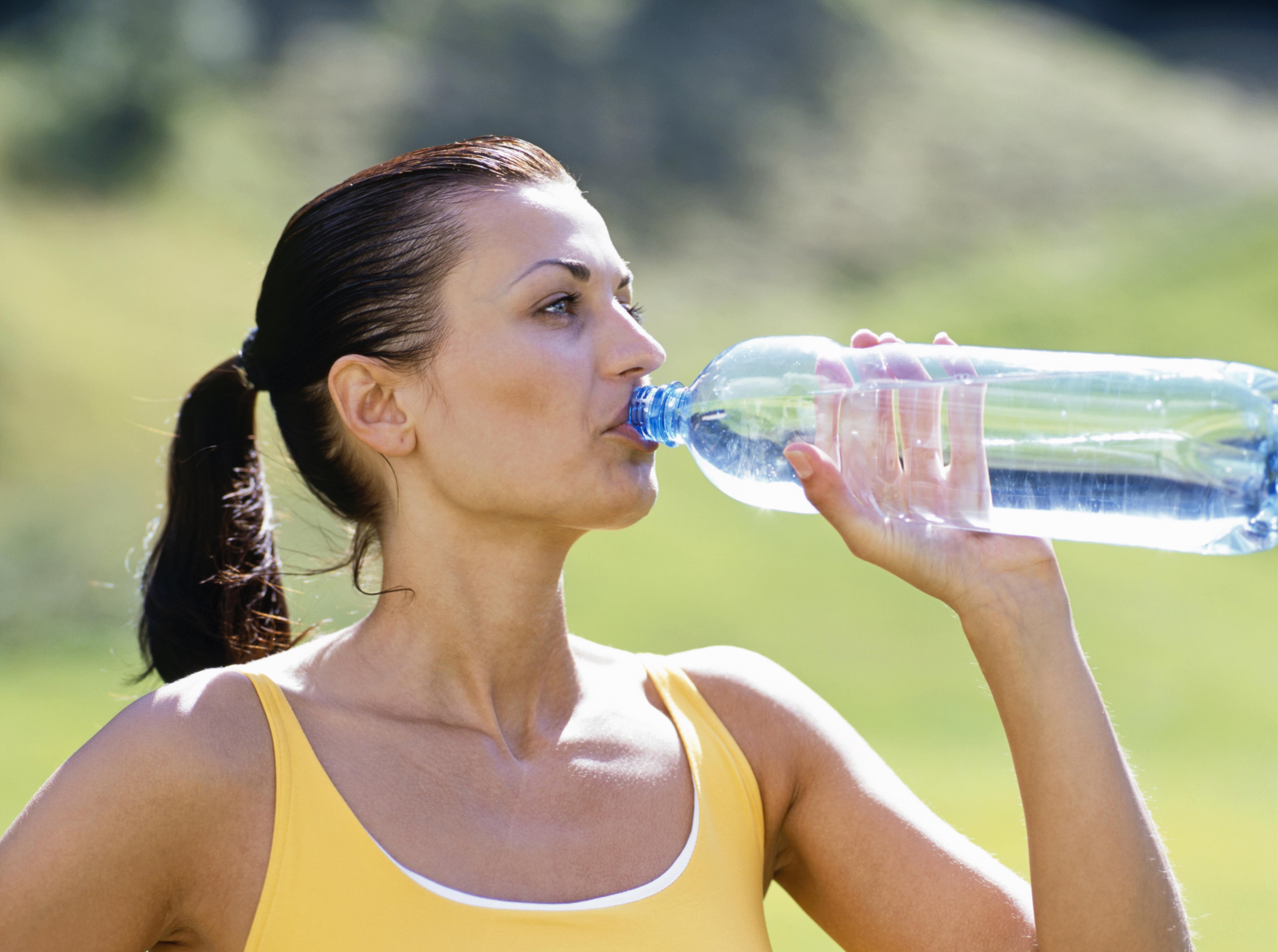 Frau trinkt Wasser aus einer Plastikflasche
