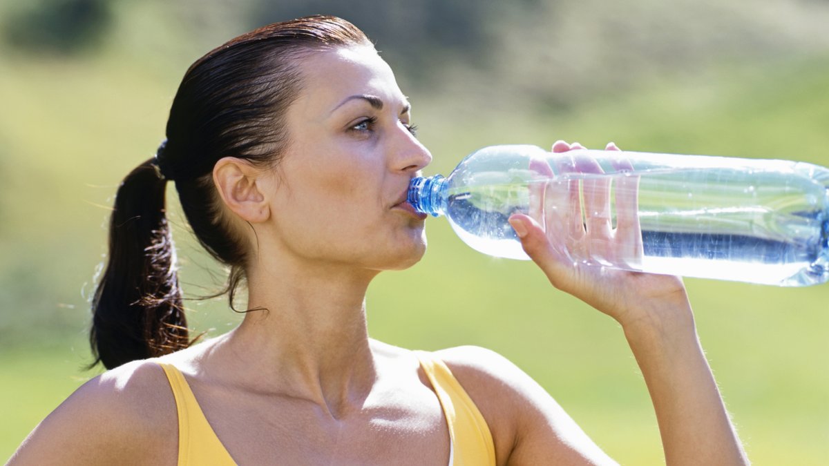 Frau trinkt Wasser aus einer Plastikflasche