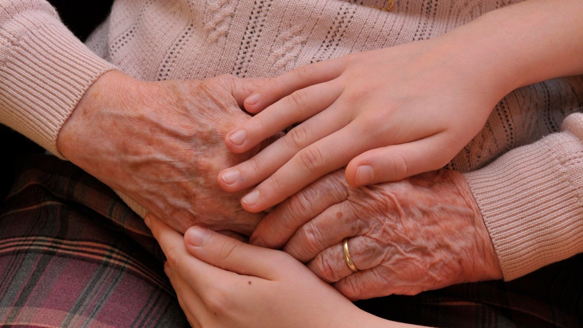 Symbolbild: Kind hält Hand von Seniorin