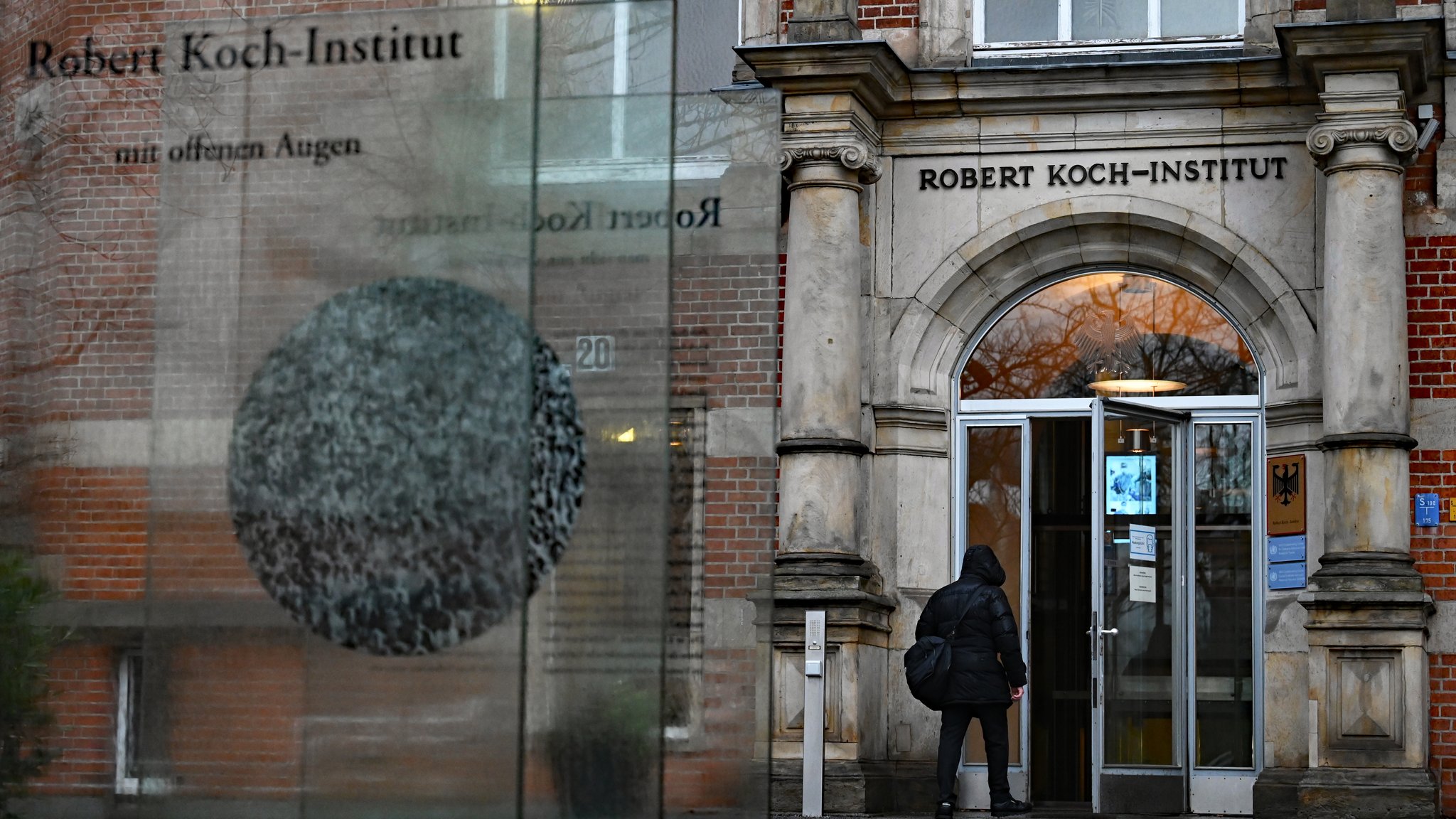 Ein Mensch geht durch den Eingang des Robert Koch-Instituts (RKI).