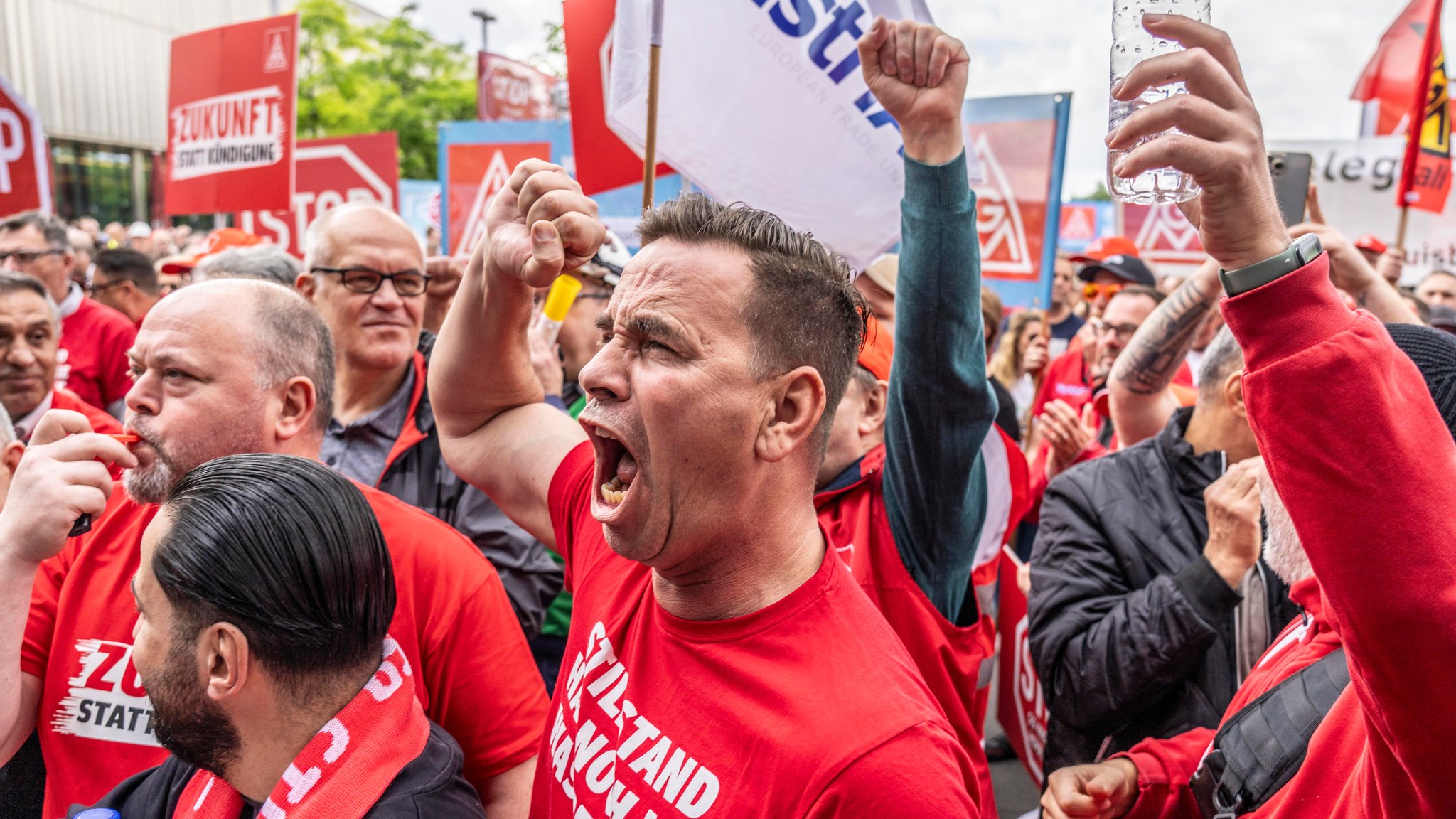 Wütende Männer recken Fäuste in die Lüfte: Demonstration von Stahlarbeitern vor der Firmenzentrale von ThyssenKrupp in Essen am 23.05.2024