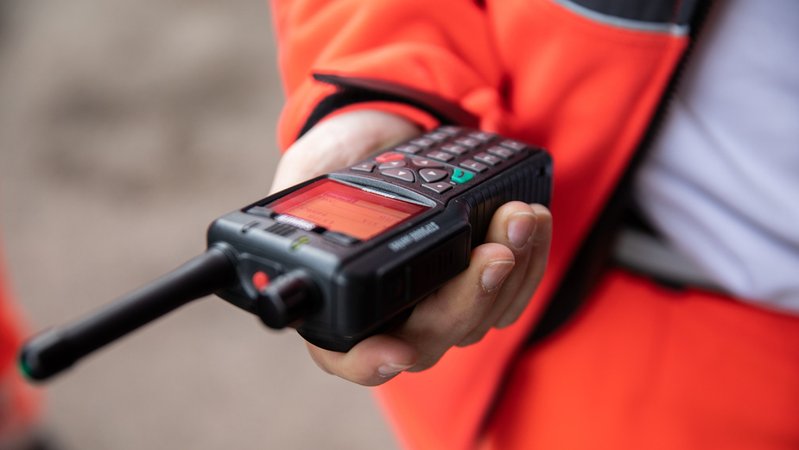 (Symbolbild) Nahaufnahme: Eine Rettungskraft hält ein Funkgerät | Bild: BR/Johanna Schlüter (Symbolbild) Nahaufnahme: Eine Rettungskraft hält ein Funkgerät