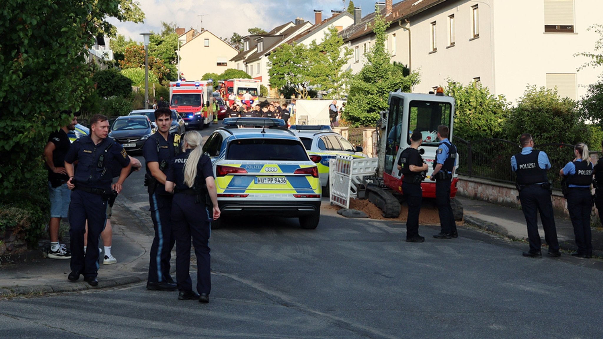 Polizisten stehen an einer Straße in der Einsatzfahrzeuge von Polizei und Rettungskräften stehen. | Bild: dpa-Bildfunk/Ralf Hettler Polizisten stehen an einer Straße in der Einsatzfahrzeuge von Polizei und Rettungskräften stehen.
