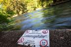 29.04.2025, Bayern, München: Ein Warnschild mit der Aufschrift ·Hier ist Baden, Surfen und Kajakfahren verboten! - ·Lebensgefahr" - Verwaltung des Englischen Gartens· weist am Ufer des Eisbach im Englischen Garten, auf die Gefahren hin. Eine Surferin, die vor Kurzem auf der Eisbachwelle im Englischen Garten stürzte, war im Krankenhaus verstorben.x Foto: Peter Kneffel/dpa +++ dpa-Bildfunk +++ | Bild:dpa-Bildfunk/Peter Kneffel