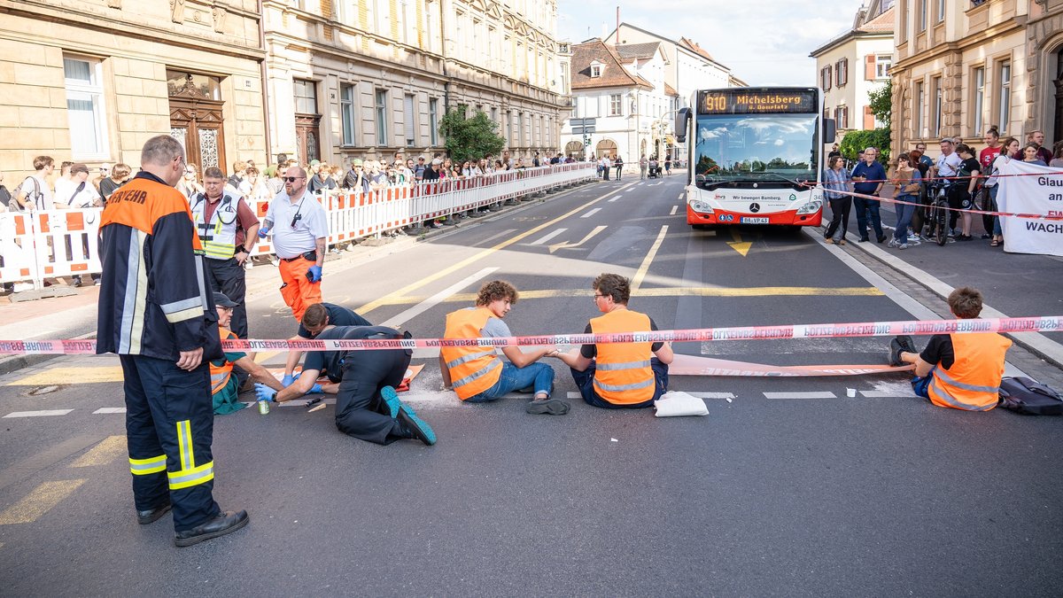 Ein Stadtbus steht vor Klimaaktivisten, die sich in Bamberg auf die Straße geklebt haben.