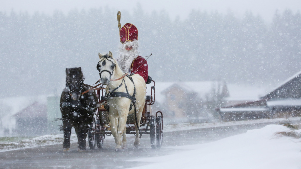 30.11.2021, Baden-Württemberg, Bad Saulgau: Ein als Nikolaus verkleideter Mann ist mit einer von zwei Ponys gezogenen Kutsche im Schneetreiben unterwegs. 