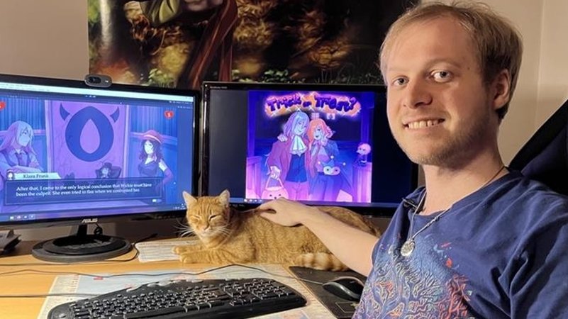Maximilian Abstreiter mit seiner Katze vor zwei Bildschirmen. | Bild: BR/Laila Heyne Maximilian Abstreiter mit seiner Katze vor zwei Bildschirmen.