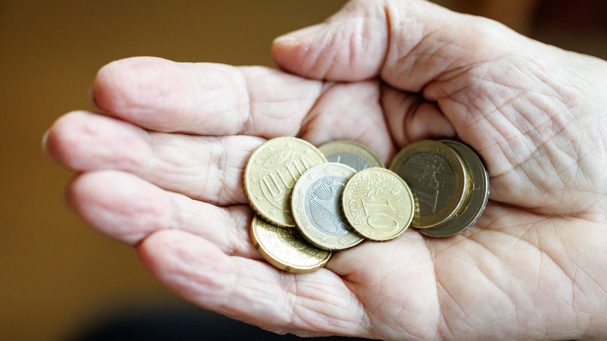 Eine ältere Dame zählt in ihrer Hand das Bargeld aus ihrem Portemonnaie ab.