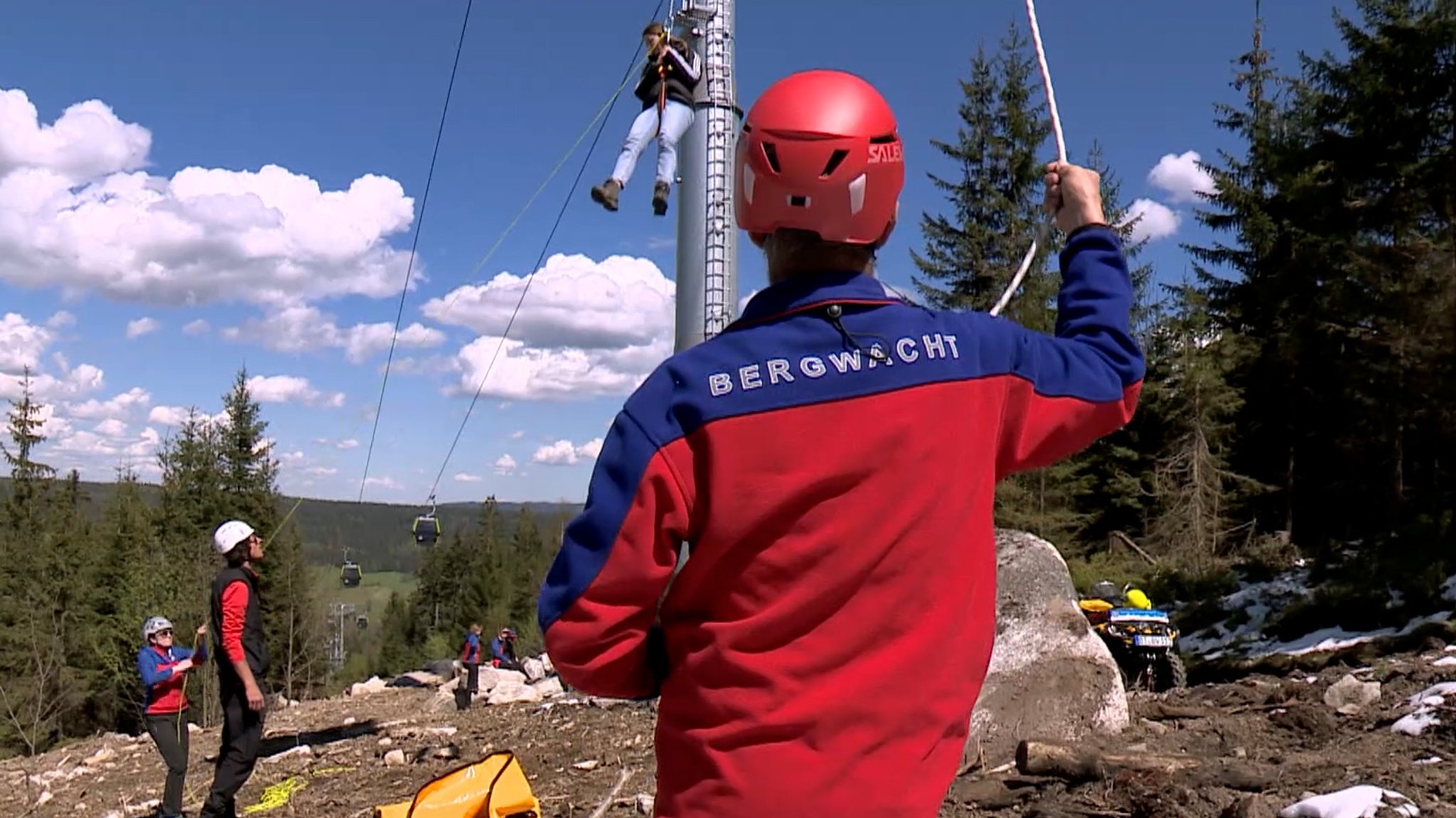 Menschen von der Bergwacht seilen gerade bei einer Übung einen Menschen aus einer Gondel ab.