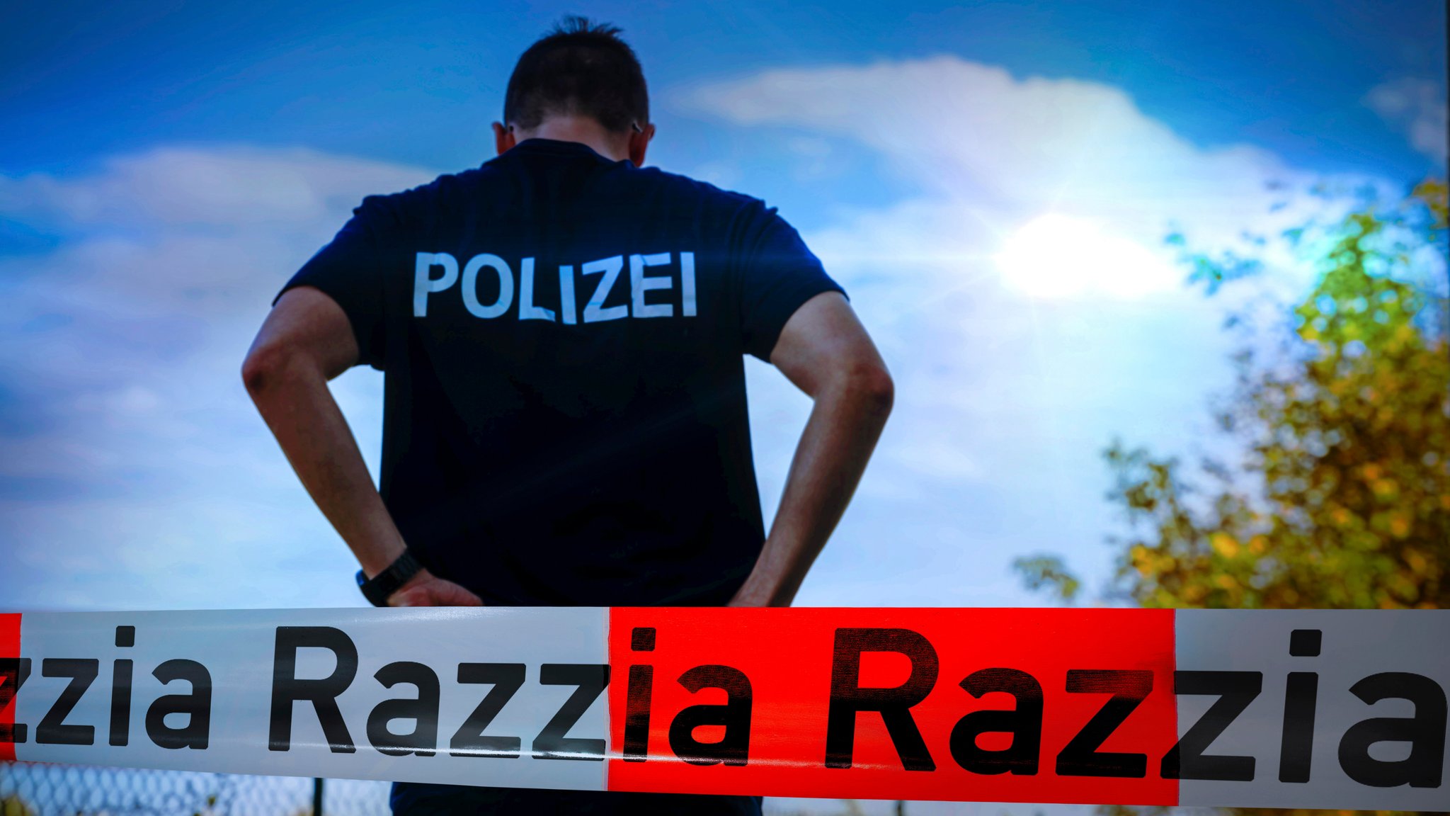 Ein Polizist an einem Einsatzort, der mit einem Absperrband gesichert wurde.