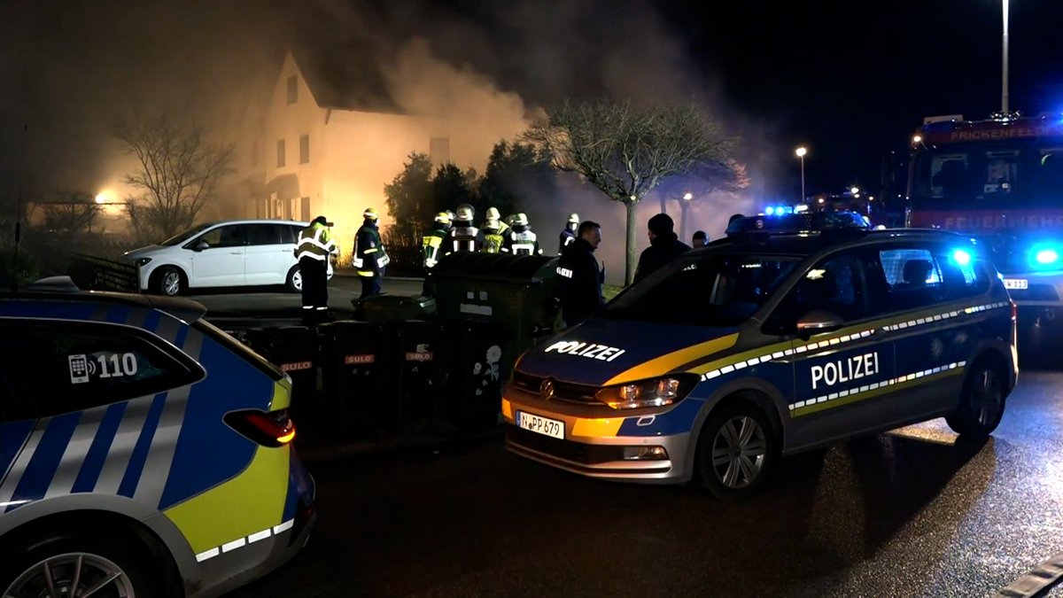 Polizeiautos und Einsatzkräfte von Polizei und Feuerwehr vor einem Haus in der Nacht.