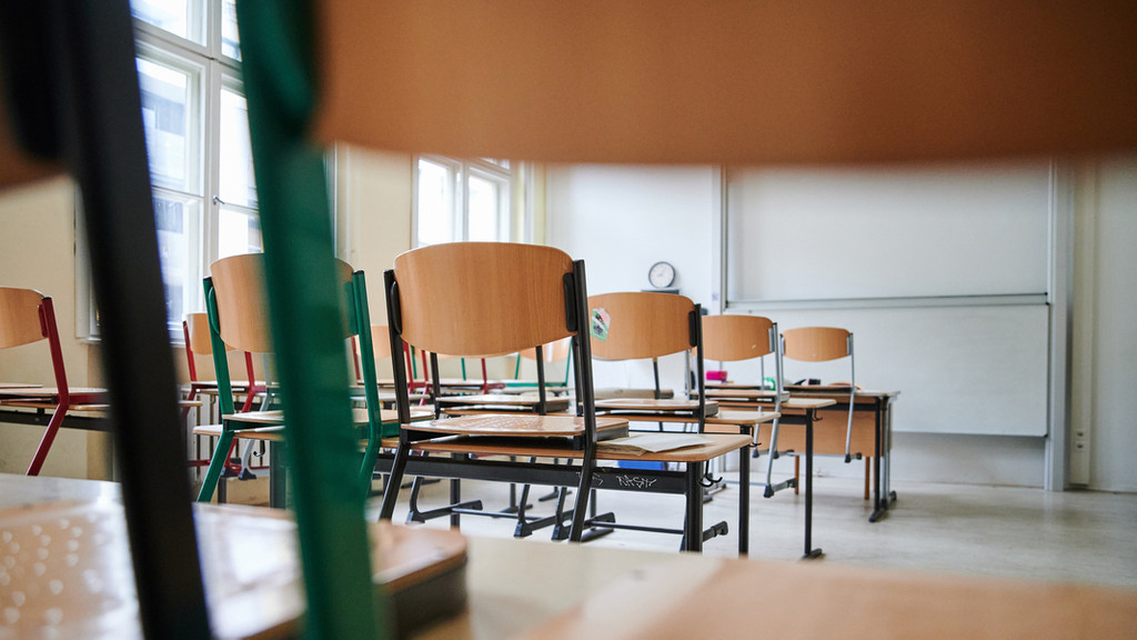 Im menschenleeren Klassenzimmer stehen die Stühle auf den Tischen.