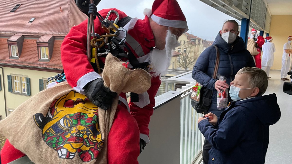 Ein verkleideter Höhenretter überbringt einem jungen Patienten seine Nikolaus-Überraschung.